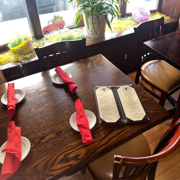 A set table at 354 Steakhouse with red napkins, menus, and Easter decorations on the windowsill.